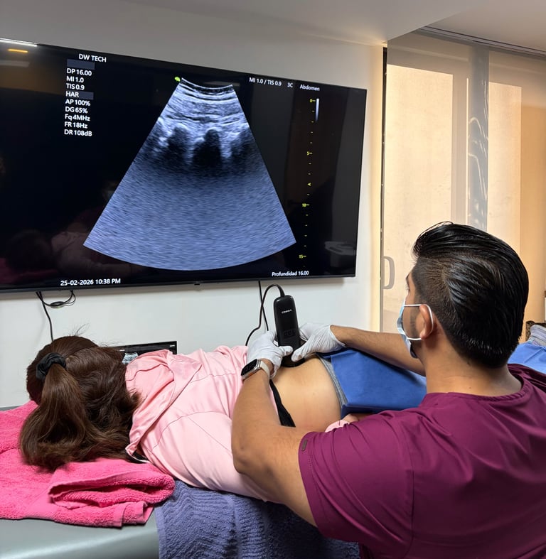 Mujer embarazada recibiendo examen de ultrasonido con su pareja a un lado mientras observan la pantalla del ultrasonido